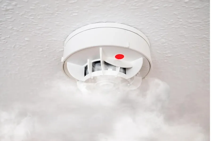services-card-smoke-alarms A ceiling smoke alarm being tested with canned smoke